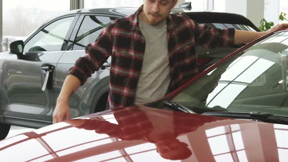 Joyful Bearded Handsome Man Embracing His New Auto at the Dealership Salon