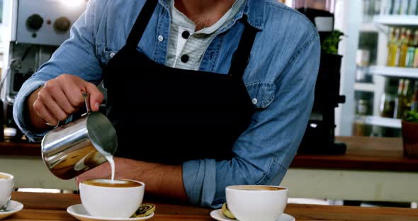 Smiling waiter making cup of coffee at counter