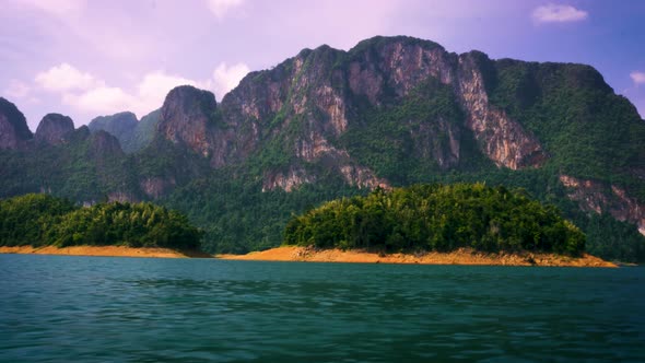 Sailing Past Small Islands On Cheow Lan Lake With View Of Limestone Cliffs At Khao Sok National Park