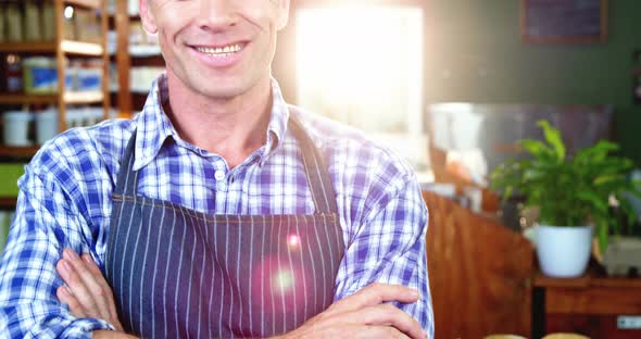 Portrait of smiling male staff standing with his hands crossed