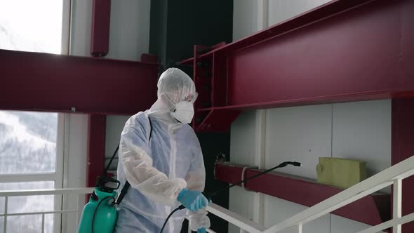 Human in Chemical Protection Suit is Disinfecting Building Inside Spraying Sanitizer on Walls