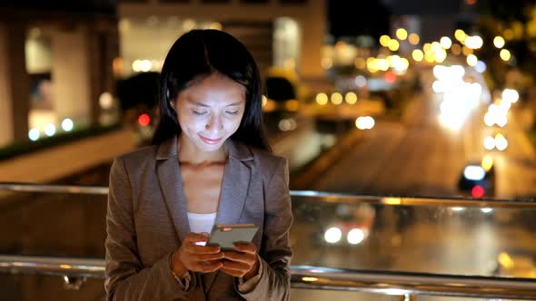 Business woman working on mobile phone at night 