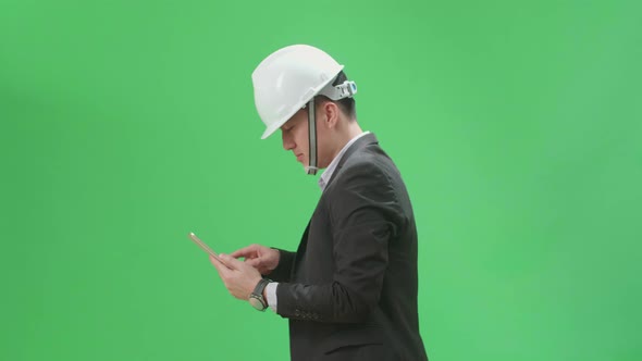 Side View Of Asian Chief Engineer In The Hard Hat Use Tablet While Walking On Green Screen