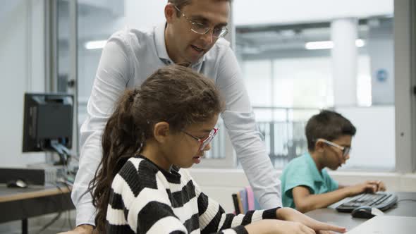 Schoolgirl and Male Teacher Working Together on Computer