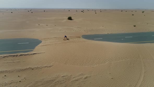 Aerial view of woman doing exercise in road cover by sand on Abu Dhabi, U.A.E