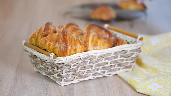 Fresh croissants in a basket on a wooden table