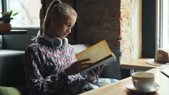 Attractive Student Reading Book in Cafe Turning Pages Enjoying Interesting Story