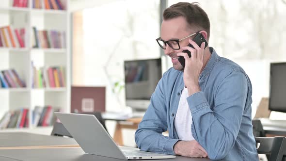 Young Man Talking on Smartphone in Office