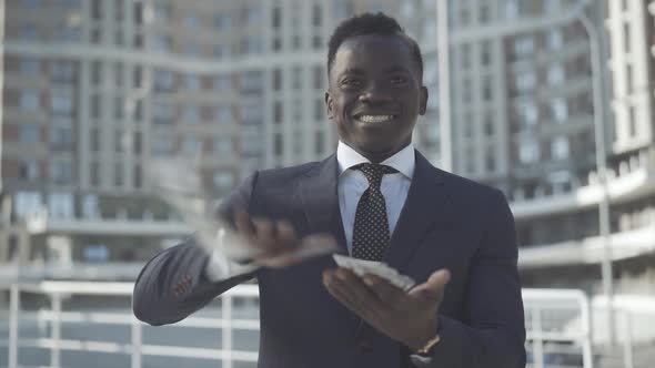 Young Successful Businessman Scattering Money and Smiling. Portrait of Wealthy African American Man