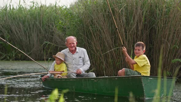 Active Childhood on River Grandfather with His Grandchildren are Fishing While Sitting in Boat