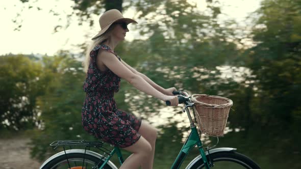 Woman In Hat Riding On Bicycle At Summer Time. Girl In Summer Dress Having Fun On Retro Bike.