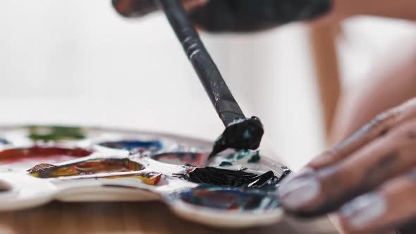 Woman Artist Takes Blue Paint with Brush From White Palette