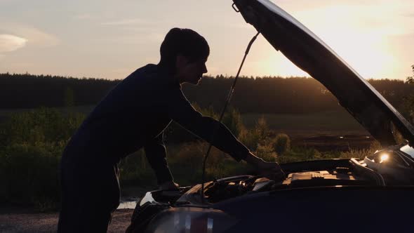 Female Looking on Engine at Sunset