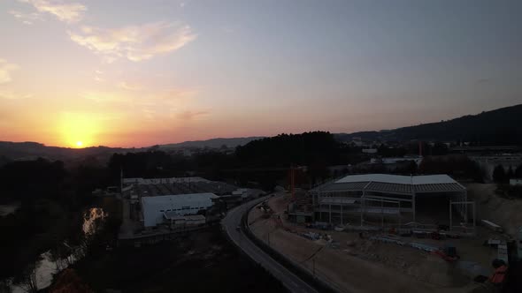 Construction site with cranes and buildings at orange yellow sunset