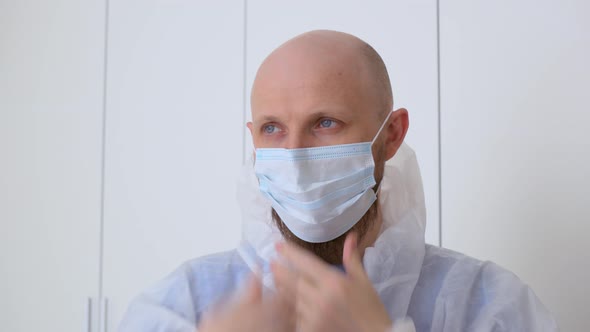 Closeup of a Bald Man in a Protective Suit Puts on a Mask to Visit the Place of Infection of the