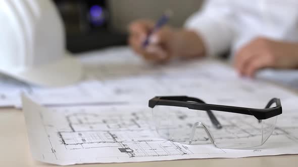 Architect making marks on construction drawings while sitting in office