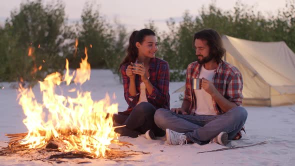 Tourist Couple Camping Near Campfire Outdoors on the Nature