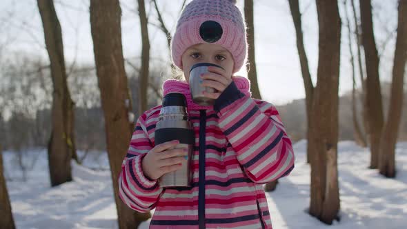 Portrait of Cute Smiling Child Girl Kid Traveler Walking Drinking Hot Drink Tea in Winter Park