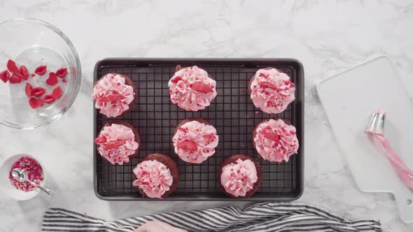 Flat lay. Step by step. Decorating red velvet cupcakes with chocolate red hearts and kisses.