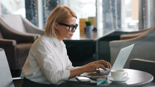 Senior Businesswoman Working with Laptop in Cafe Typing Looking at Screen