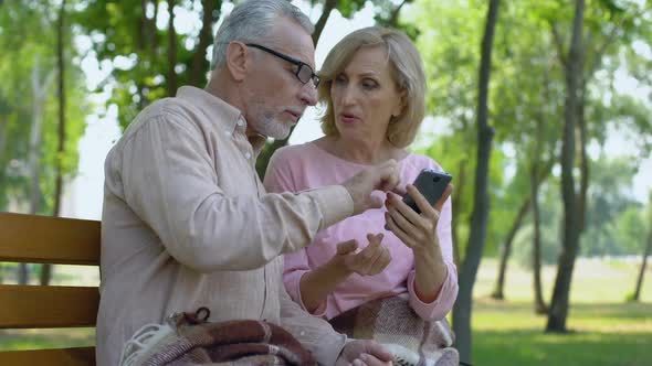 Old Man Helping Aged Wife Use Smartphone, Happy Senior Couple Together in Park