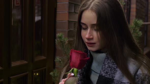 Attractive Girl Inhales Scent of Red Rose Smiles