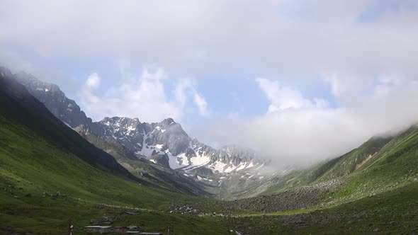 High Snowy Mountains on the Background of Glacial Valley and Alpine Meadows