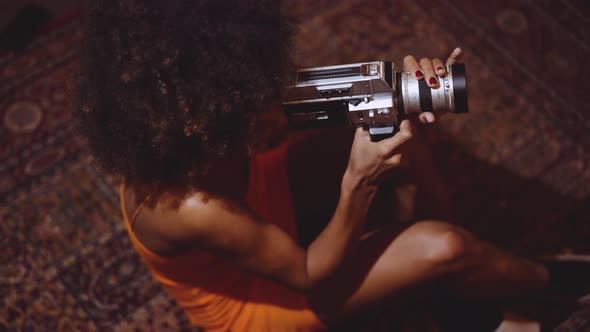 Woman With Afro Hair In Orange Dress Using Vintage 8Mm Camera