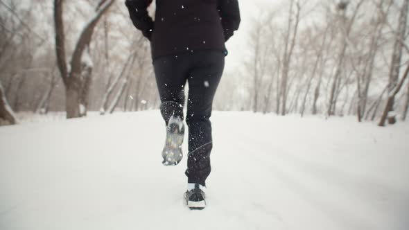 Sporty Woman in Black Jacket and Sports Sneakers Runs Along Winter Park Legs Closeup Back View