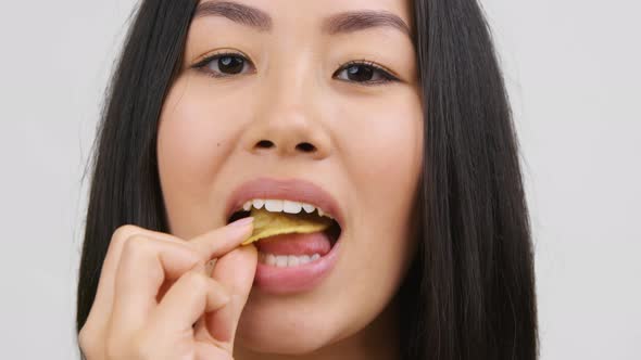 Chinese Woman Eating Crispy Potatoes Chips On White Background Closeup