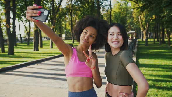 Happy Diverse Female Friends Making Selfie on Smartphone During Walk in Park Tracking Shot