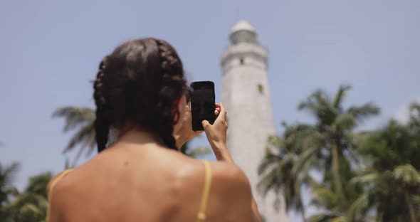 Woman Traveler in Front of Famous Landmark of Sri Lanka with Smartphone Dondra Lighthouse