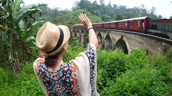 Woman Traveler Waving To Train Driving On Nine Arch Bridge