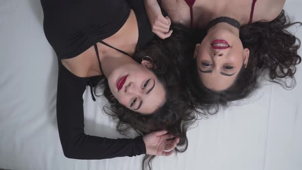 Two Charming Colombian Girls Relaxing While Lying On Bed