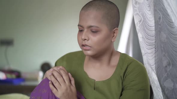 Worried and hopeless cancer patient bald Asian girl is sad and crying at home, after chemotherapy