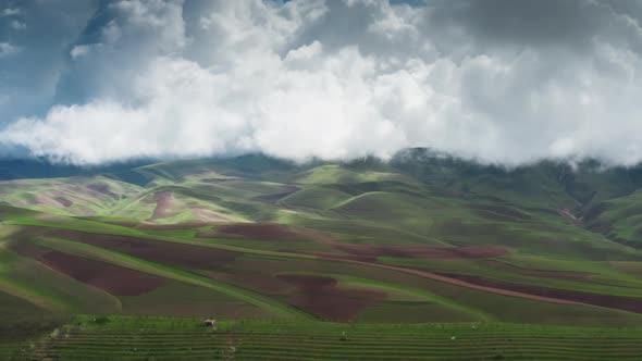 A Magnificent Aerial Landscape with Green Hills and Brown Plowed Lands Under Huge White Swirling