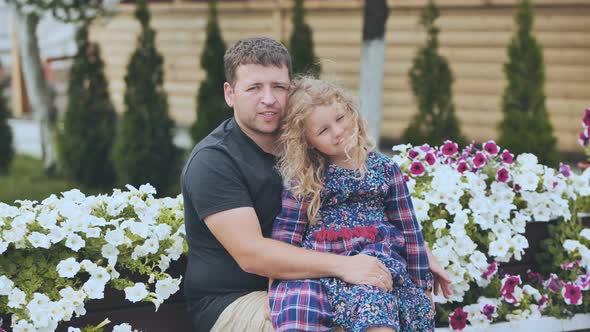 A Portrait of a Father with His Young Daughter in the Garden Against a Background of White Petunias