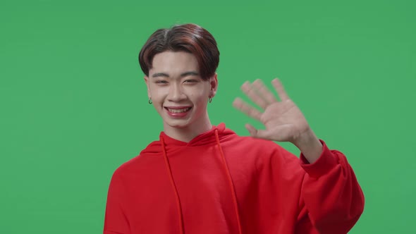 Happy Asian Transgender Male Waving Hands And Looking At Camera In The Green Screen Studio