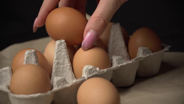 Woman's Hand Takes a Chicken Egg From a Container