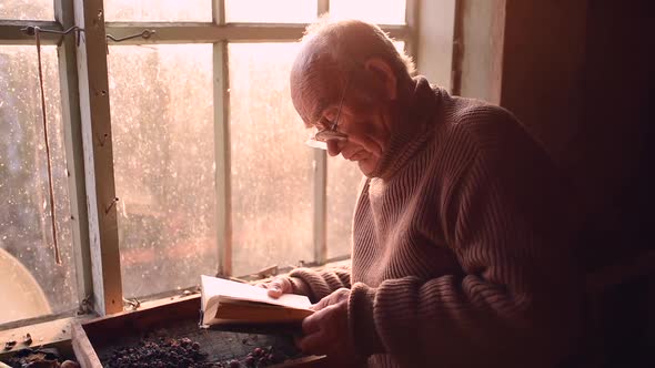 Man Glasses Picks Up Old Book in Dust Read in House Window