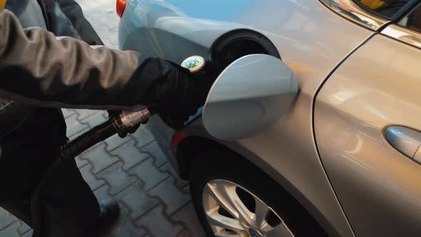 Person Refueling Car's Tank. Gas station worker in workwear refueling luxury car with gasoline 