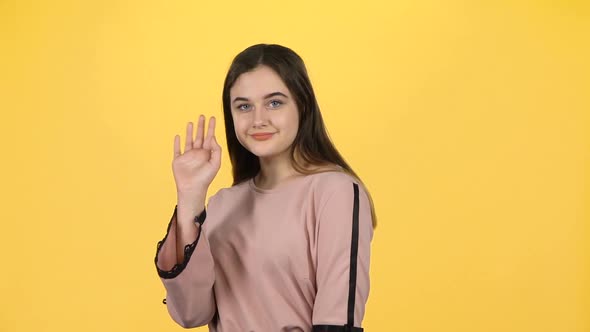 Youngful Girl Waving with Hands on Yellow Background. Slow Motion