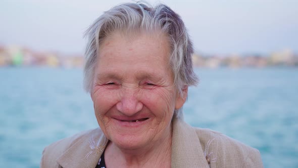 Grey Haired Woman Laughs Standing on Embankment in Chioggia