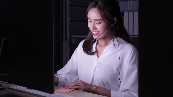 Beautiful young female Asian call center working at night, wearing headphone