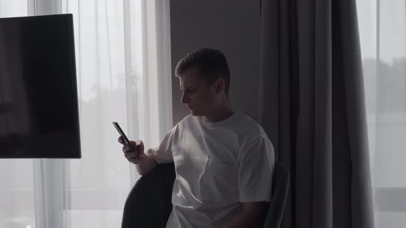 The Groom is Sitting with the Phone in the Hotel Room