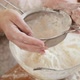 Top View of Female Baker Sifting Flour with Sieve in Big Glass Bowl for Making Dough - VideoHive Item for Sale