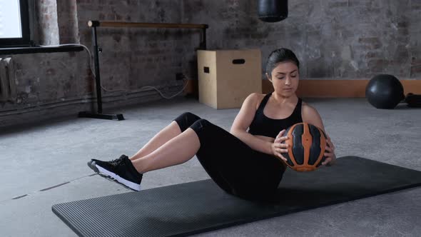 Young Indian Athletic Woman Doing abdominal Press Exercise Works Hands and Feet Uses Ball 