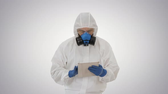 Epidemiologist in Hazmat Suit and Respirator Mask Using Digital Tablet While Walking on Gradient