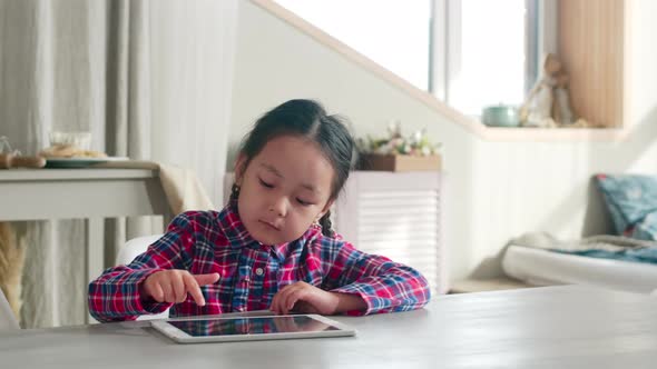 Asian Girl Playing on Digital Tablet at Home