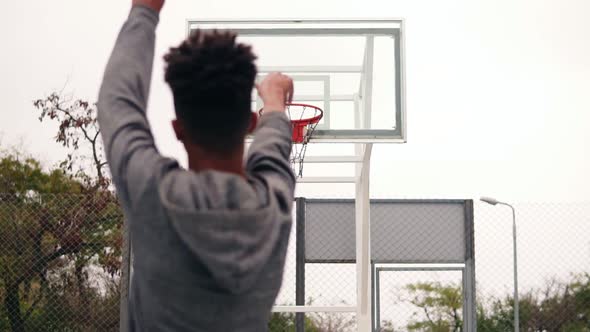 Back View of Unrecognizable African Player Throwing Ball in a Basketball Hoop the Ball Hits the Ring